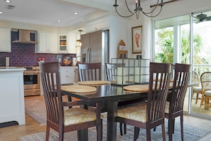A modern kitchen with a dining table, chairs, and a view of the outdoors. - 🌴Boardwalk Bungalow | Steps to Beach | Pool | Pet Friendly🌴 (Cape San Blas)