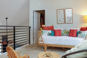 A bedroom with a bed, a chair, a small table, and a balcony railing. - 🌴Boardwalk Bungalow | Steps to Beach | Pool | Pet Friendly🌴 (Cape San Blas)