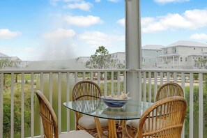 A glass-top table with chairs on a balcony overlooking a residential area. - 🌴Boardwalk Bungalow | Steps to Beach | Pool | Pet Friendly🌴 (Cape San Blas)