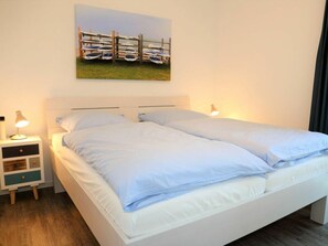 Ein Schlafzimmer mit einem Bett, zwei Nachttischen, einem Wandbild und einer Ablagefläche.