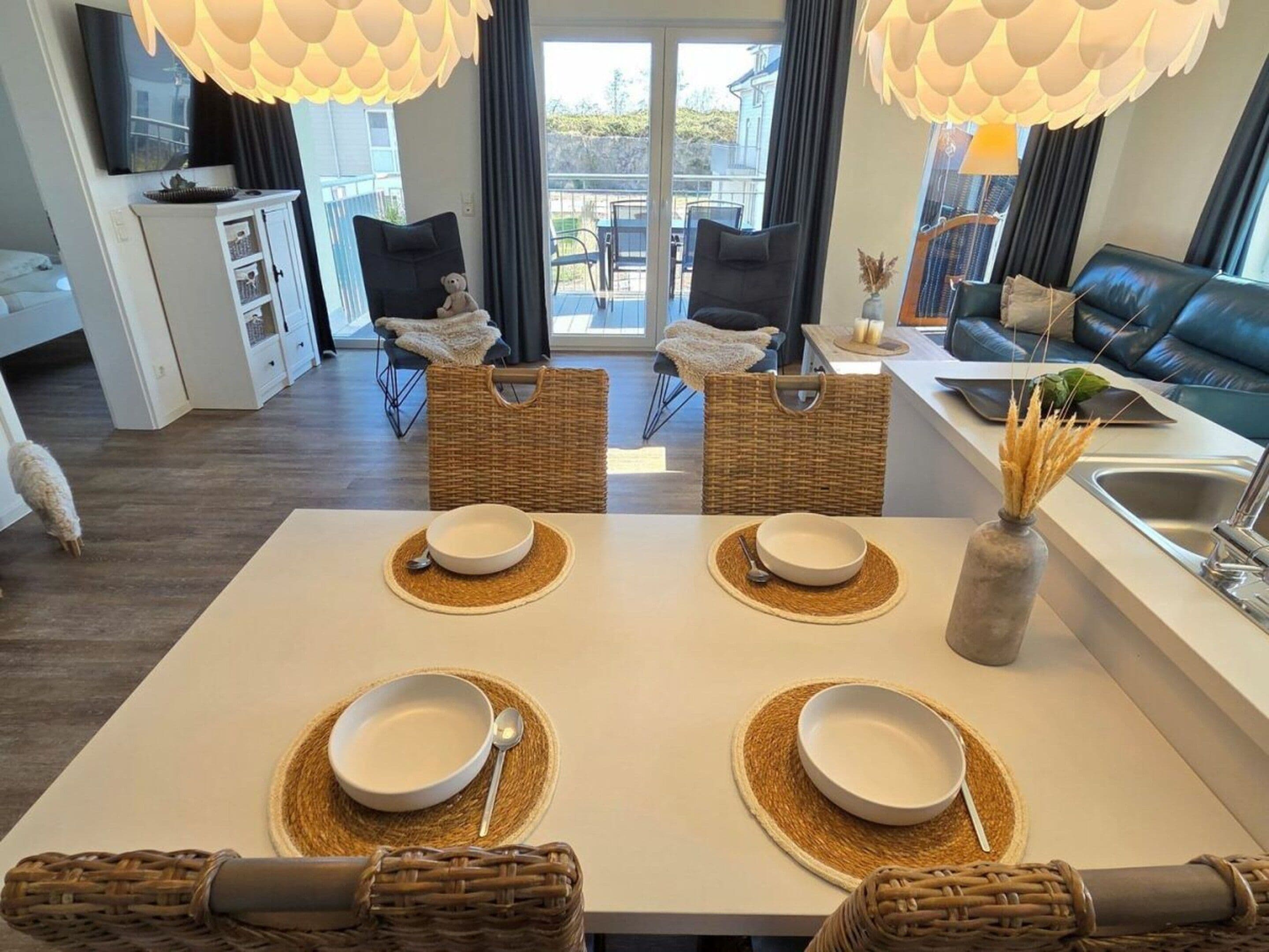 A modern dining area with a table set for four, two chairs, a wicker basket, and a vase with dried plants.