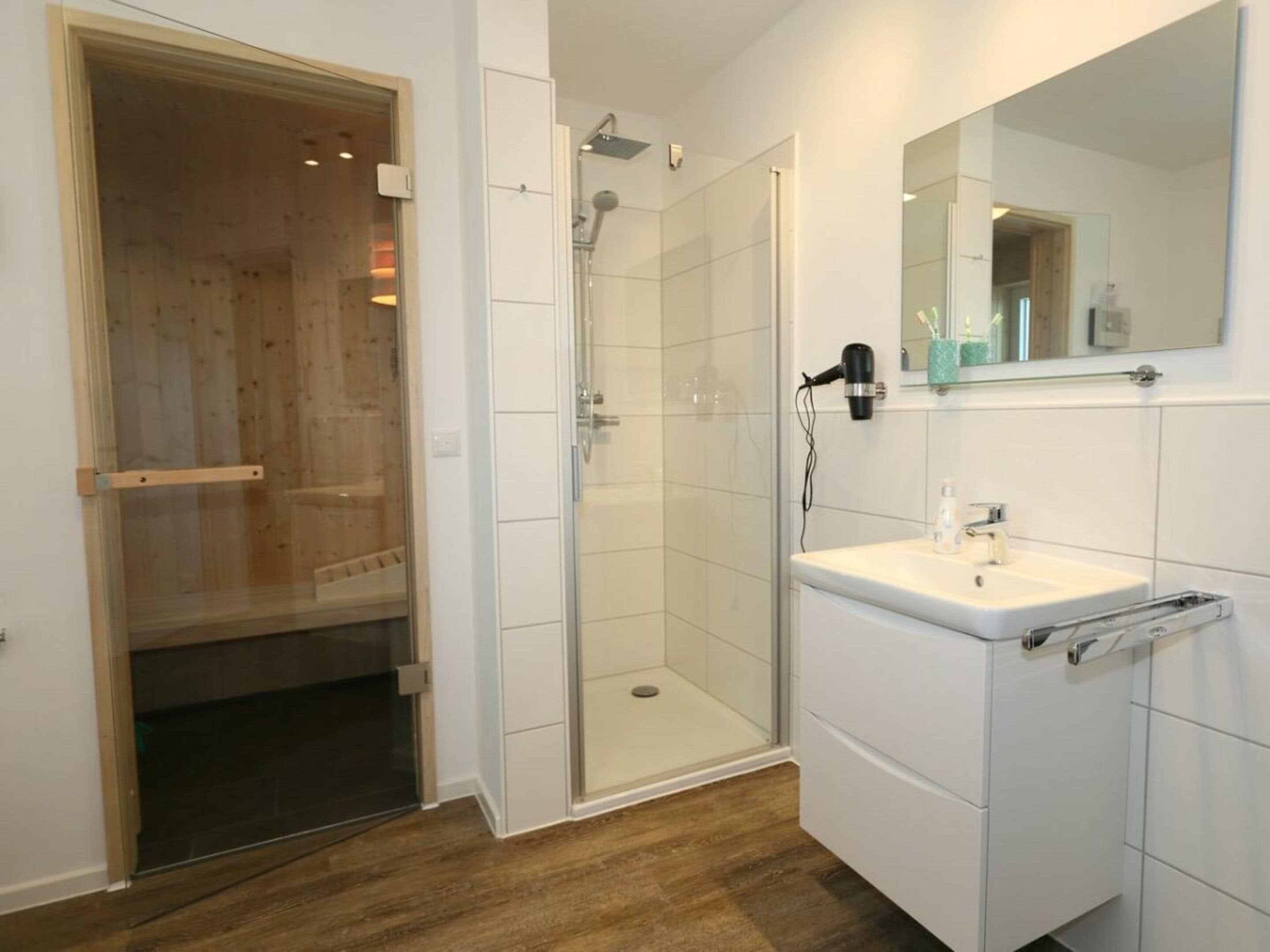 Un bagno con doccia, lavandino e specchio.