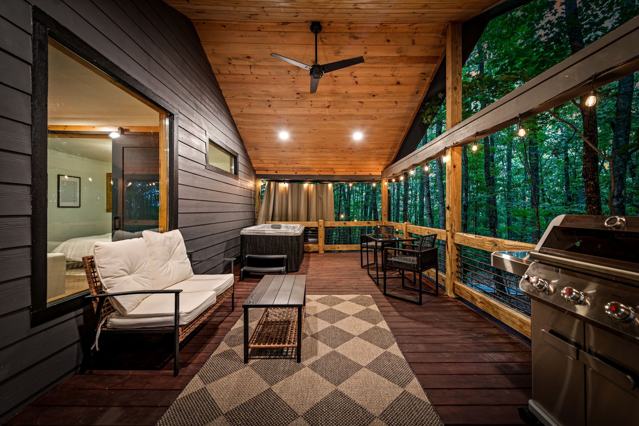 Eine gemütliche Terrasse im Freien mit Holzboden, Grill, Sofa und Essbereich.