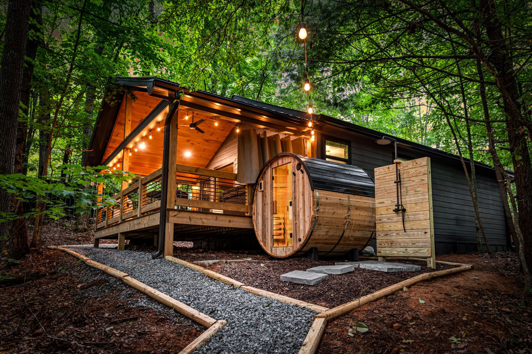 Eine Holzhütte mit einer großen, trompetenförmigen Tür und einer Terrasse mit Lichterketten.