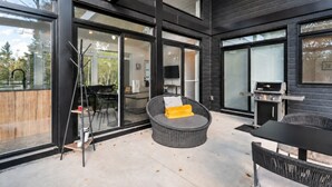En moderne udendørs terrasse med spisebord, stole og grill.