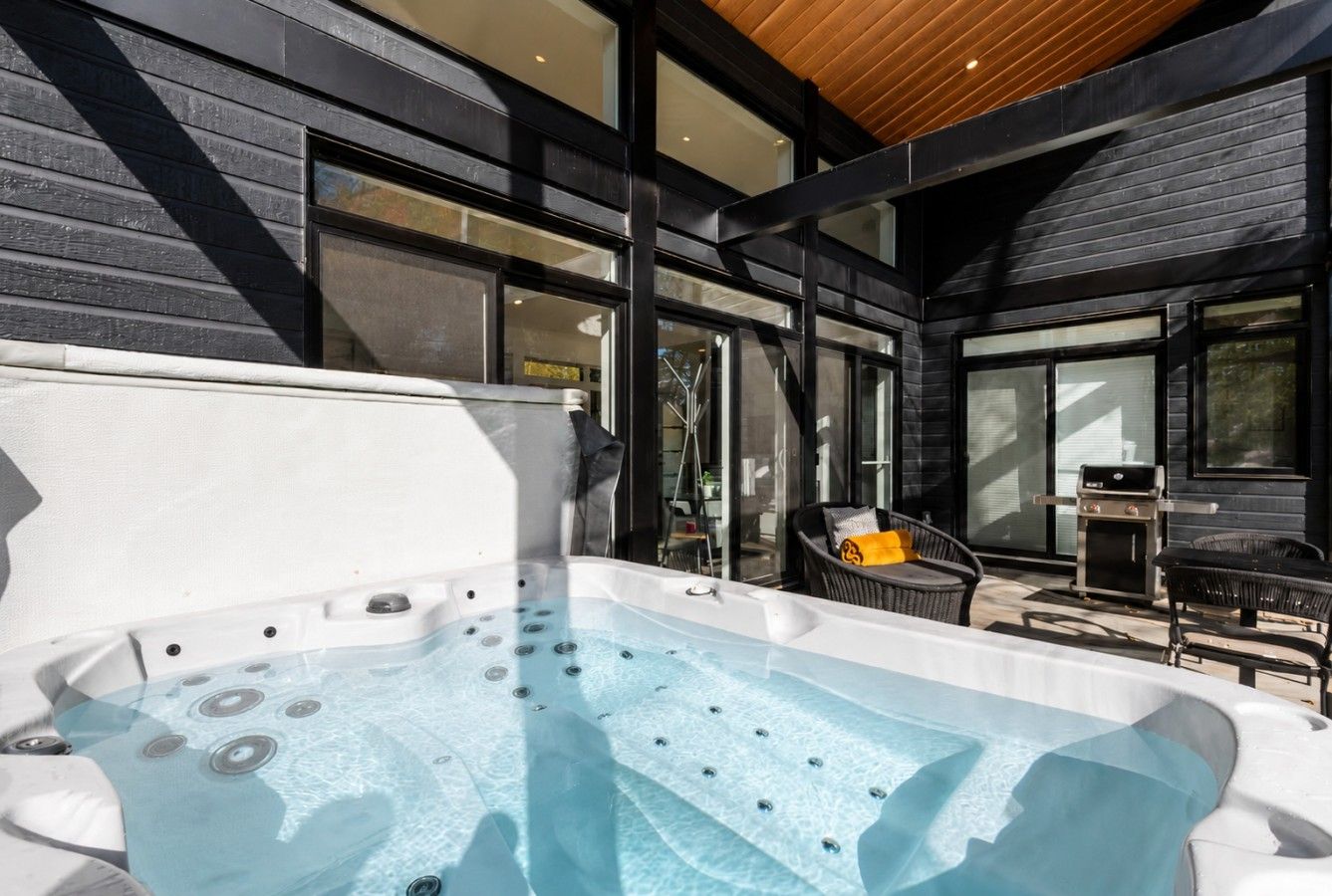 Un bain à remous avec un plafond en bois et un barbecue à l’extérieur.