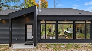 A modern house with a dark exterior, large windows, and a visible outdoor area with a statue.