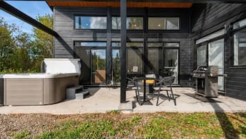 Eine moderne Terrassengrundstück mit Whirlpool, Grill und Gartenmöbeln.