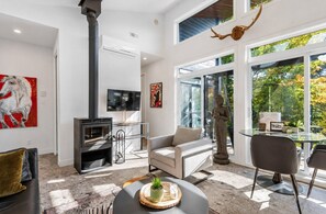 A modern living room with a fireplace, a sofa, a dining table, and a statue.