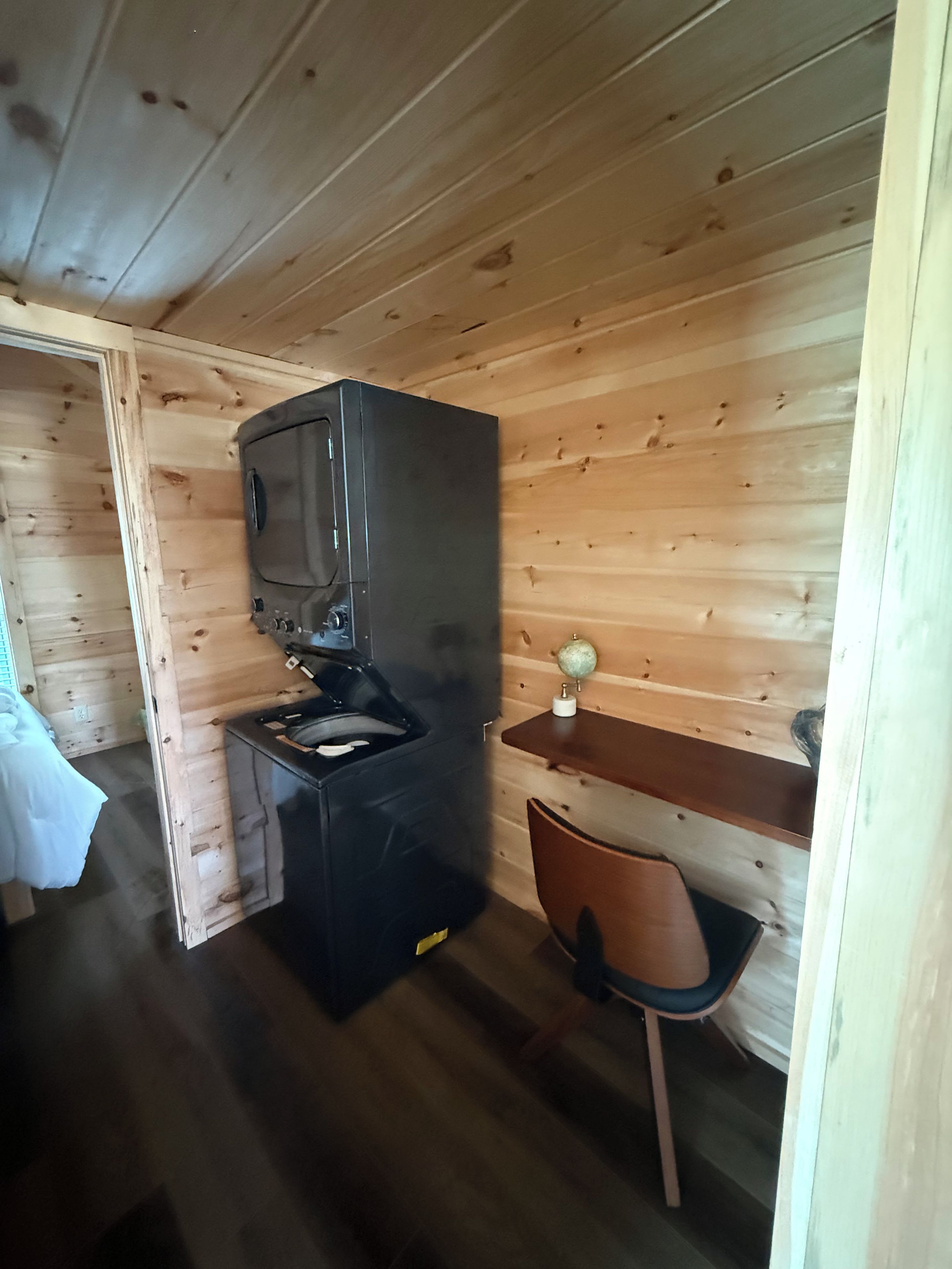 Cocina compacta con estufa, lavamanos y una pequeña zona de comedor con una silla.