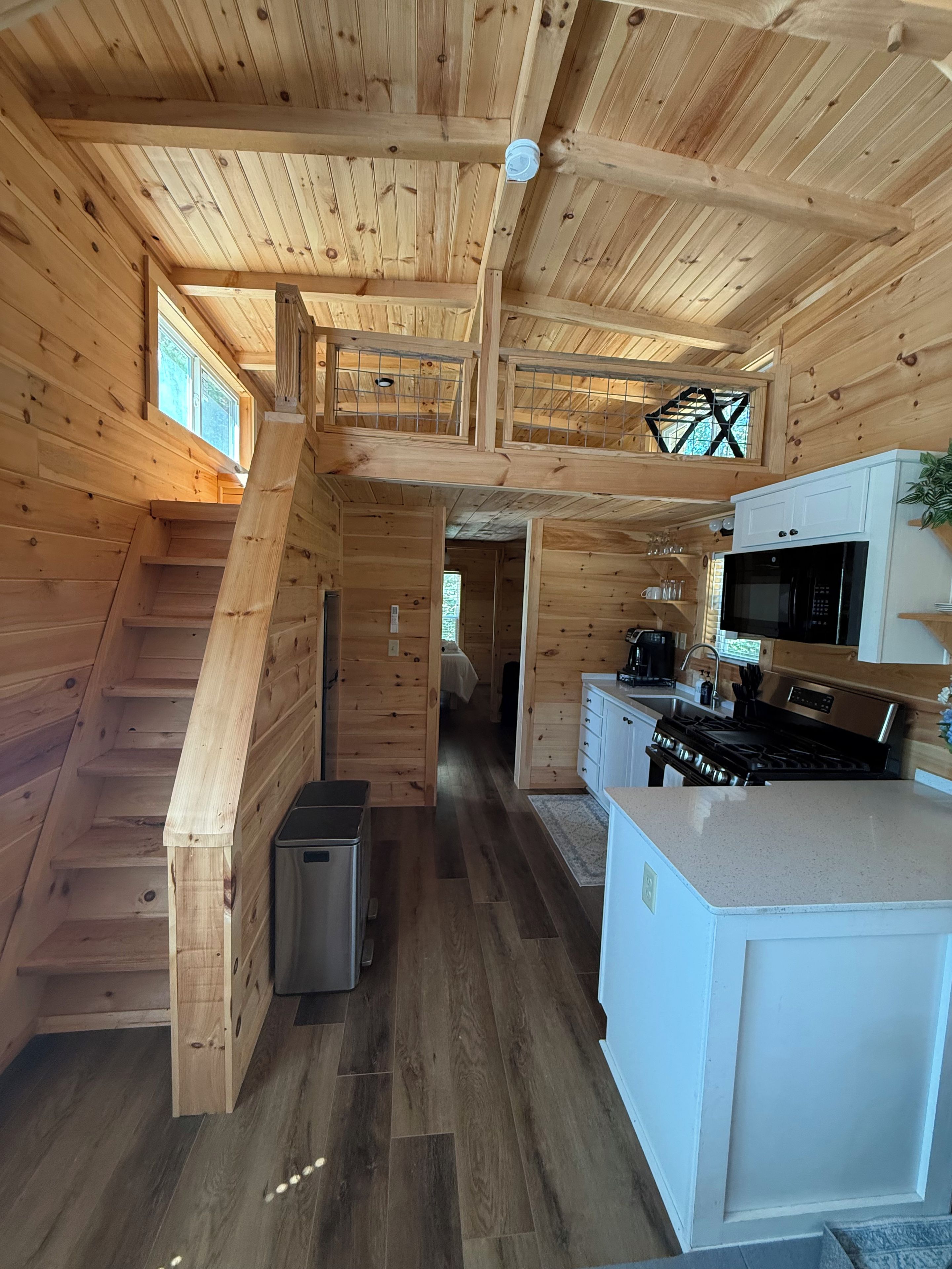 L’intérieur d’une cabane en bois comprend une cuisine, un coin repas et un escalier menant à un étage supérieur.