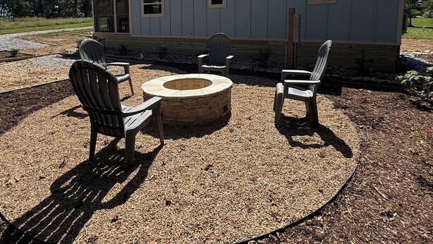 A house with a covered outdoor seating area, including a fire pit and chairs.