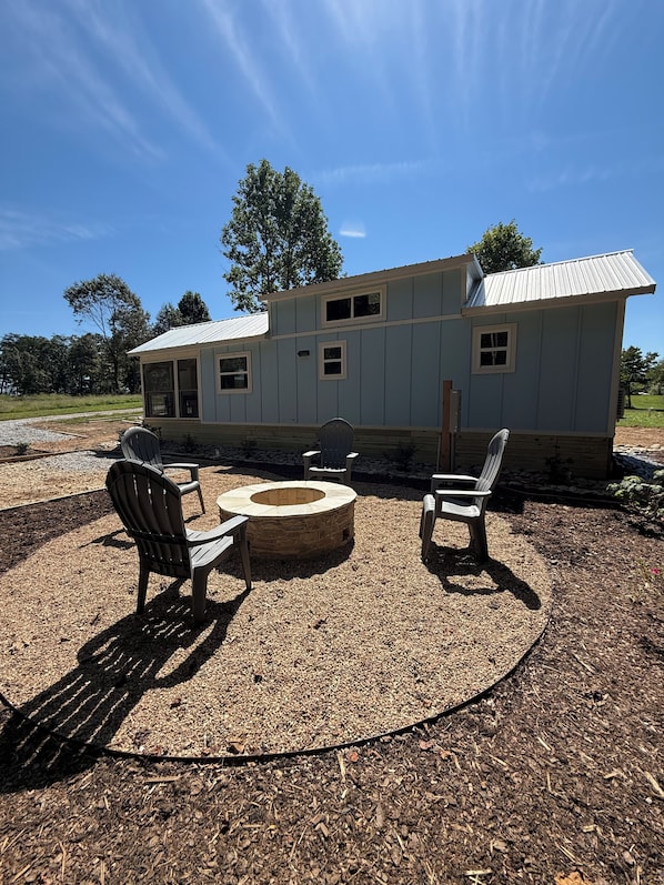 A house with a covered outdoor seating area, including a fire pit and chairs.