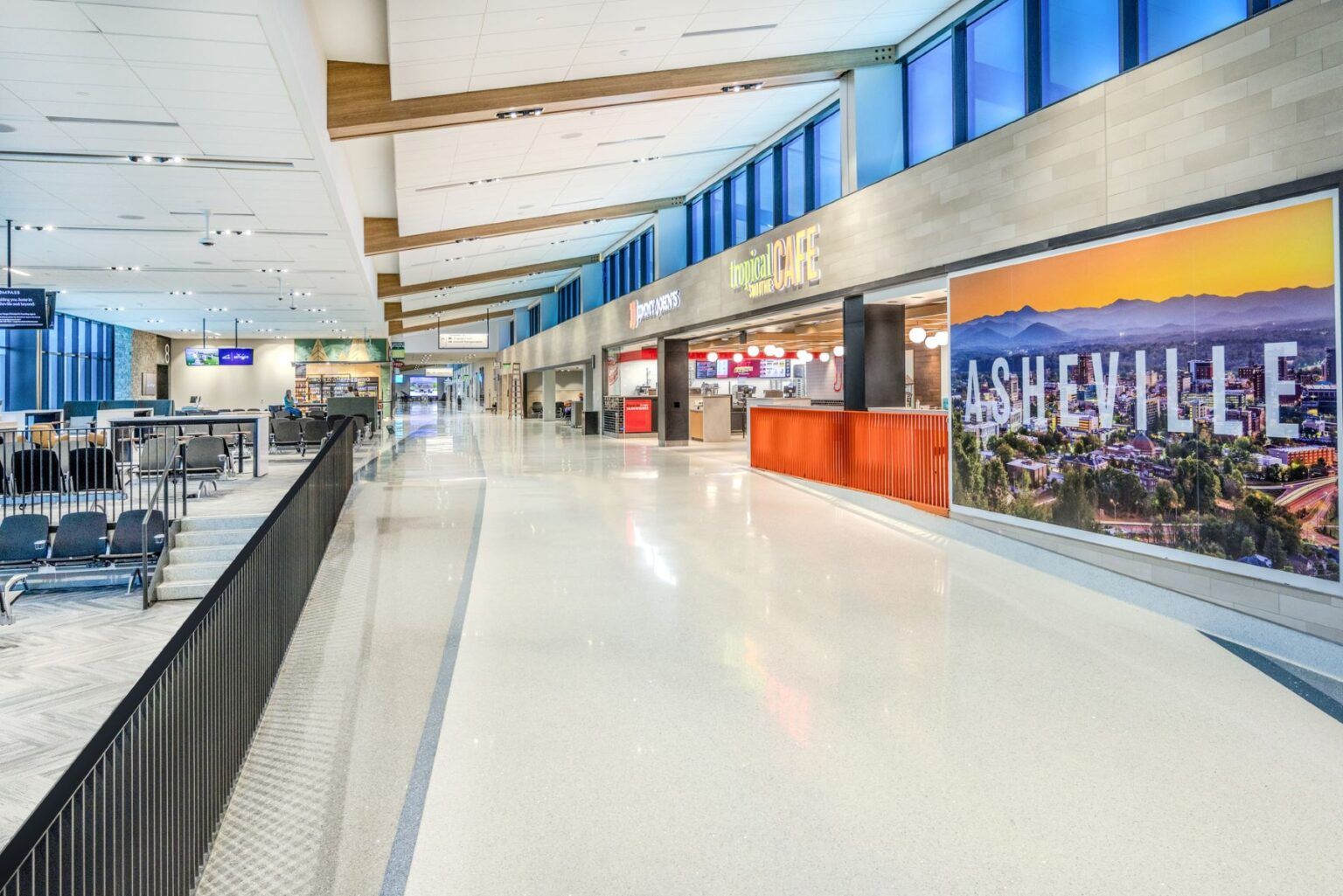 Un vaste terminal d’aéroport doté d’un café à l’ambiance tropicale et d’une grande fresque représentant un paysage urbain.