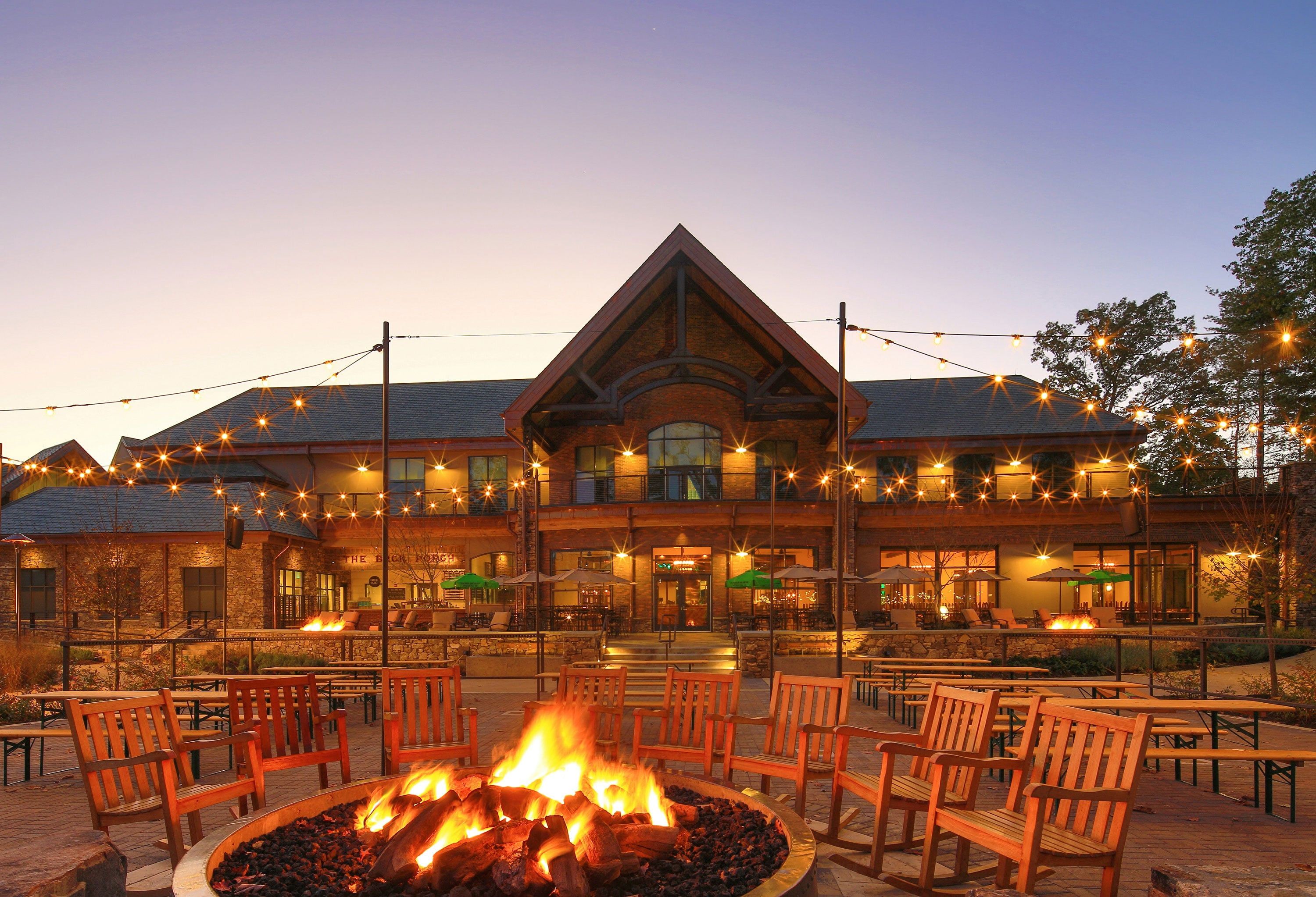 A building with a fire pit in the center, surrounded by wooden benches and tables.