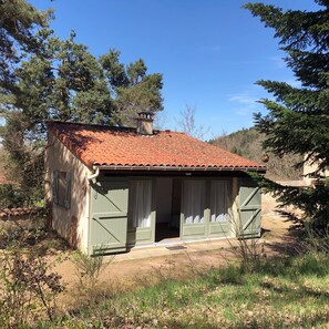 A rustic cabin with a tiled roof, a chimney, and a door leading to an interior space.