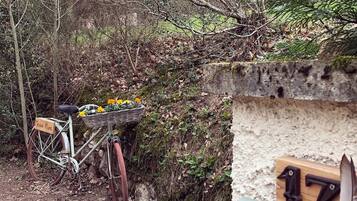 A rustic bicycle with a basket of flowers parked near a stone wall with a number plaque.