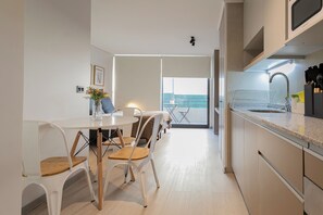 Eine moderne Küche mit Essbereich, Blick auf den Balkon und einem großen Fenster.