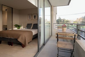 Ein Schlafzimmer mit Bett, Nachttisch, Sessel und einem Balkon mit Blick.
