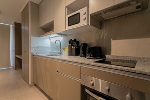 Eine moderne Küche mit Mikrowelle, Kaffeemaschine und Edelstahlgeräten.