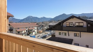 En by belägen i bergen med traditionell arkitektur, klar himmel och utsikt över snöklädda berg.