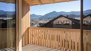 En träbalkong med utsikt över ett bergskedja och bostadshus.