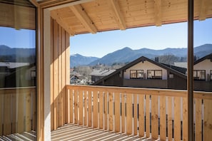 Un balcón de madera con vistas a una cordillera y edificios residenciales.