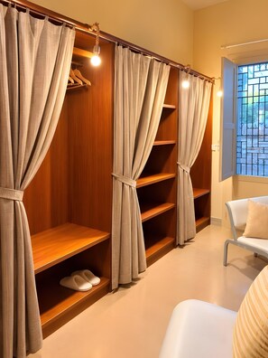A walk-in closet with wooden shelves and grey curtains.