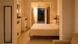 Een hotelkamer met een bed, een stoel, een nachtkastje en uitzicht op de omgeving.