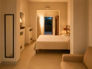 A hotel room with a bed, a chair, a bedside table, and a view of the outdoors. - Villa “Masseria Baba” with Private Pool, Wi-Fi, and Air Conditioning (Nardò)