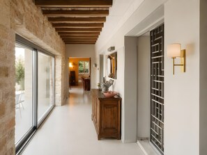 Un pasillo con un banco de madera, un aplique en la pared y un ventanal grande.