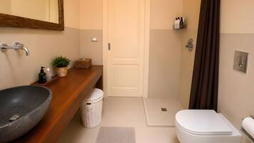 Ein Badezimmer mit Holzwaschtisch, großem Waschbecken, Toilette, Dusche und Spiegel.