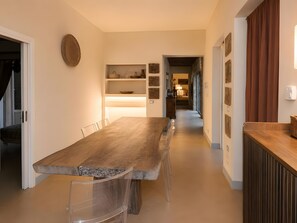 A modern kitchen with a long wooden table, built-in shelves, and a view into the dining area. - Villa “Masseria Baba” with Private Pool, Wi-Fi, and Air Conditioning (Nardò)