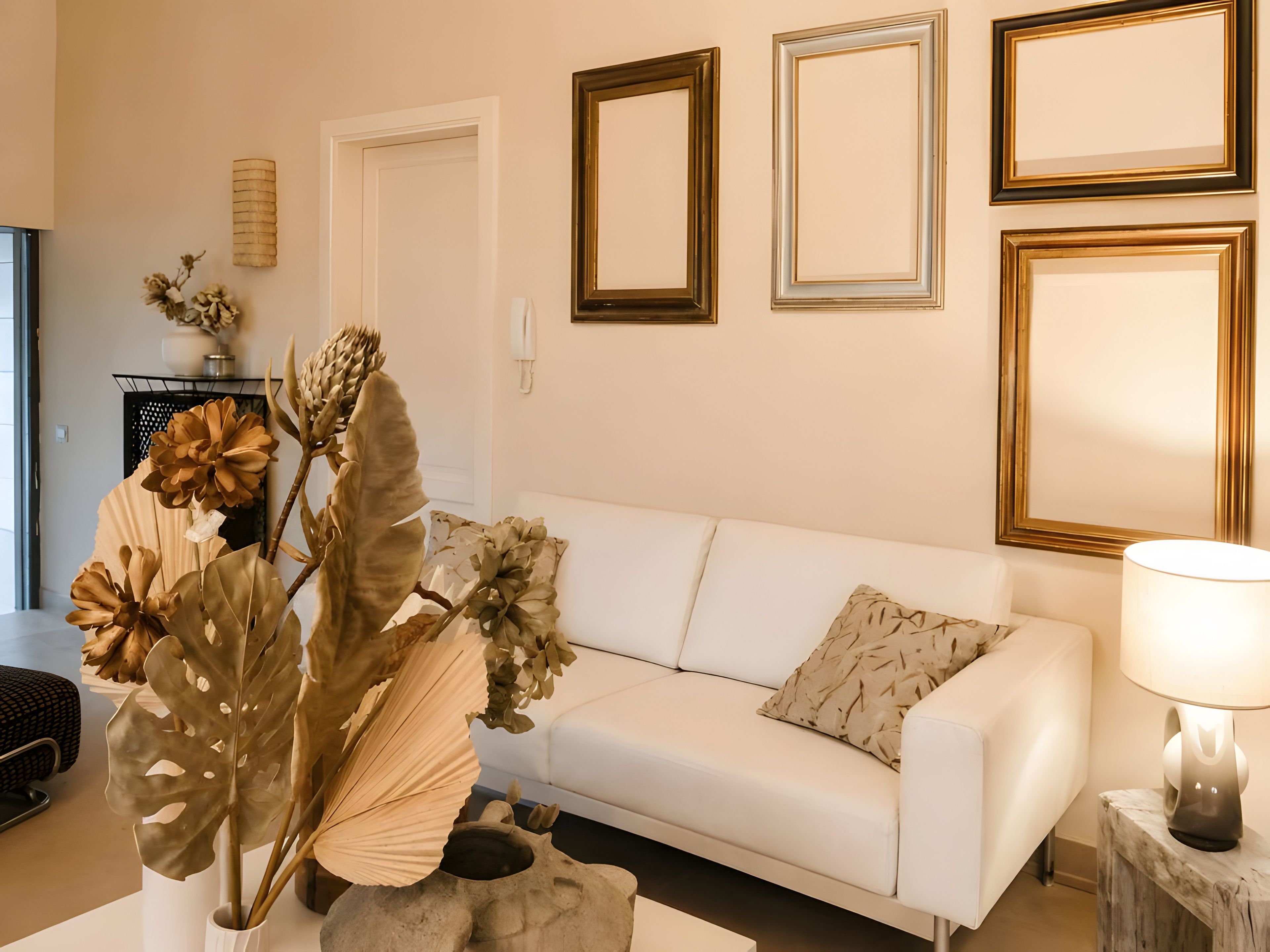 A modern living room with a white sofa, decorative plants, and framed artwork on the wall.
