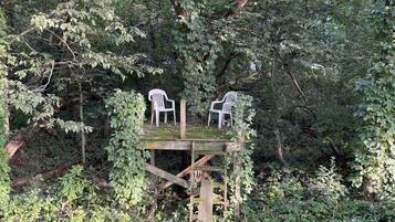 A wooden treehouse with two white plastic chairs.