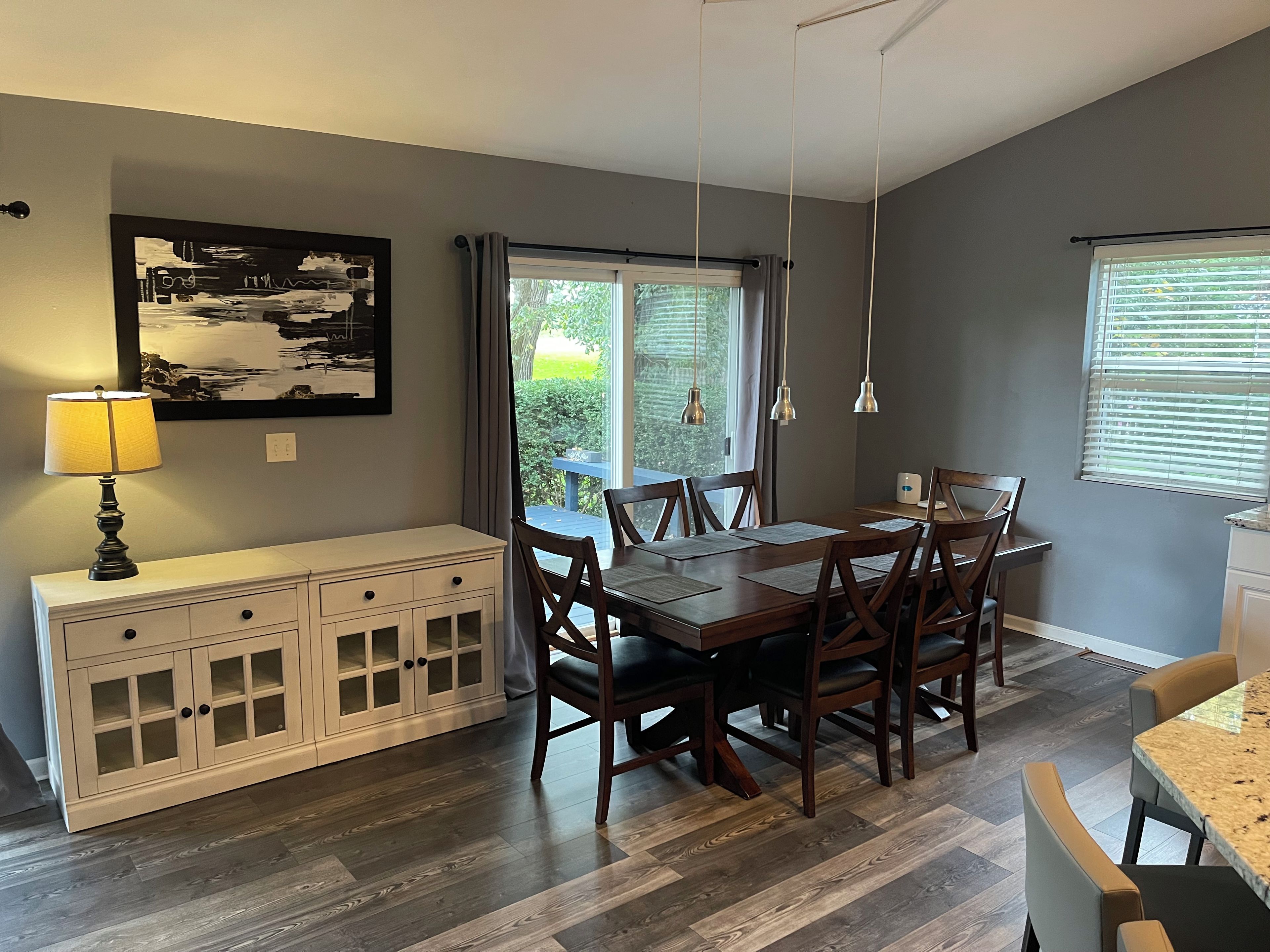 Un coin repas avec une table et des chaises en bois, un buffet blanc et un tableau au mur.