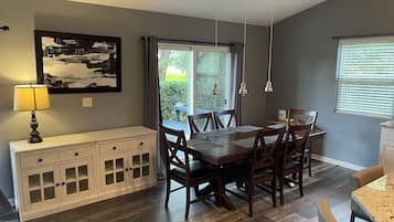 Un coin repas avec une table et des chaises en bois, un buffet blanc et un tableau au mur.