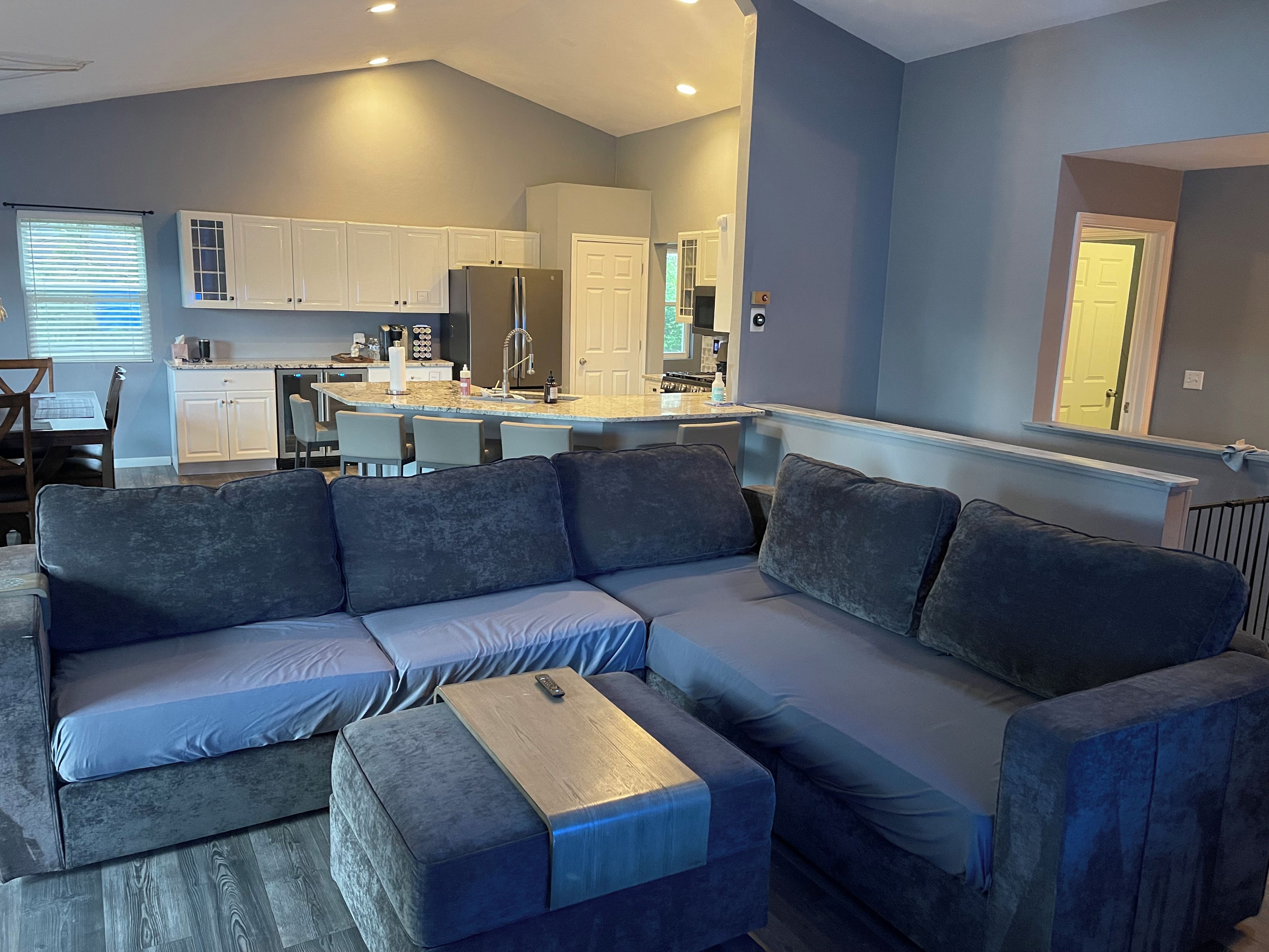 A modern living room with a sectional sofa, a wooden coffee table, and a kitchen in the background.