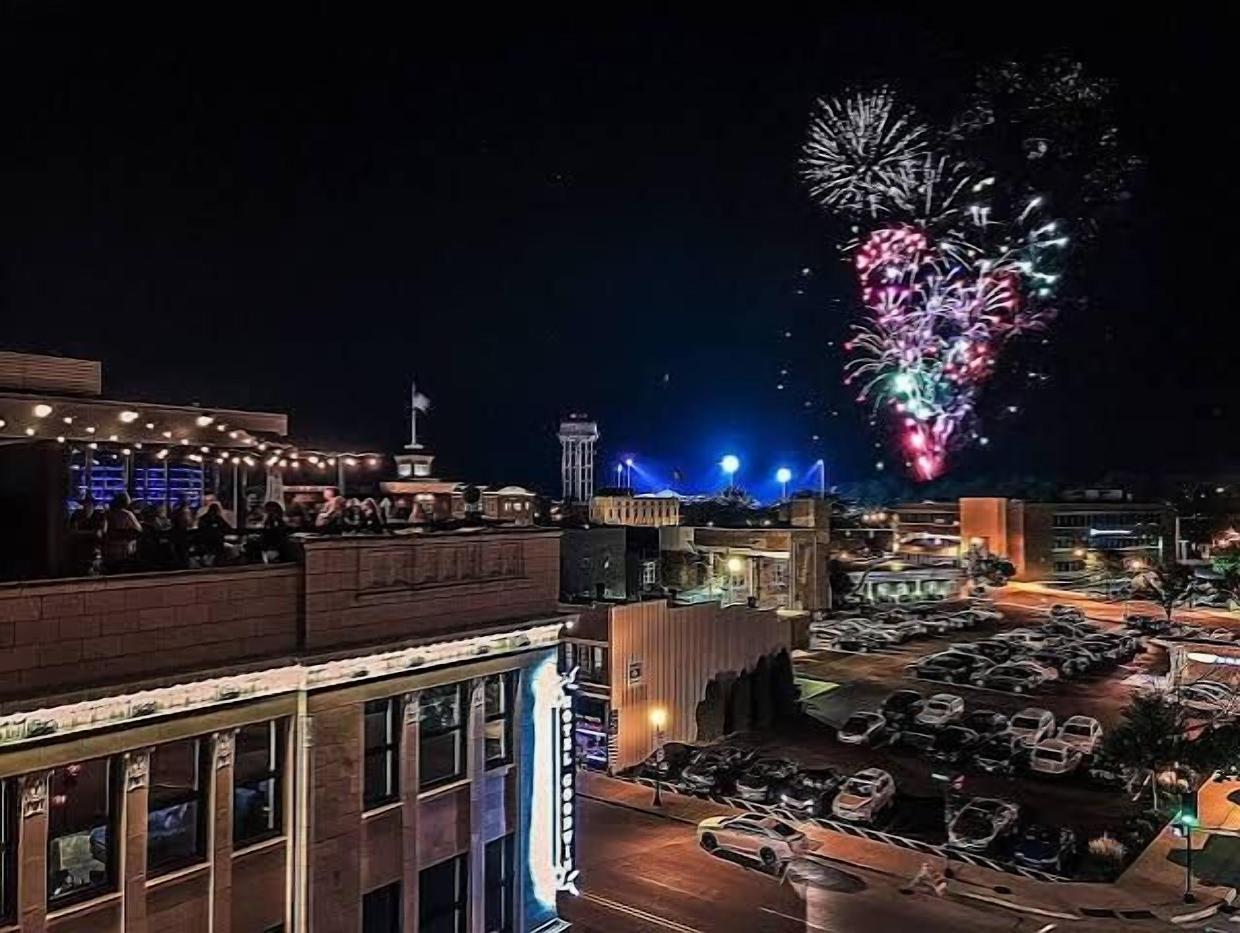 Un bar situé sur un toit, offrant une vue sur la ville et les feux d’artifice.
