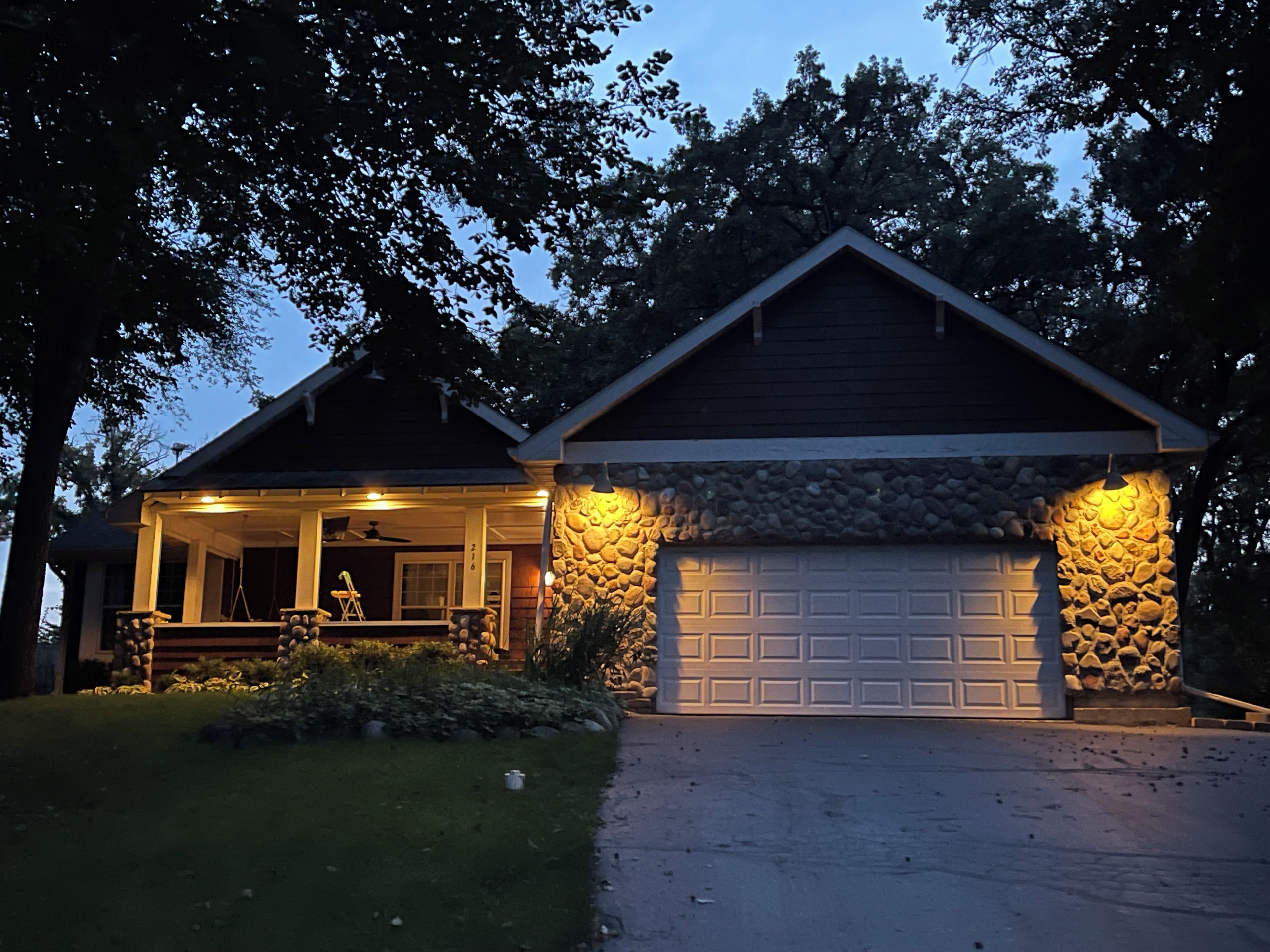Une maison d’habitation avec une façade en pierre, un garage et une véranda.