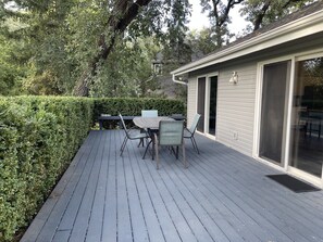 Eine Terrasse mit Tisch und Stühlen, umgeben von einer Hecke und Bäumen.