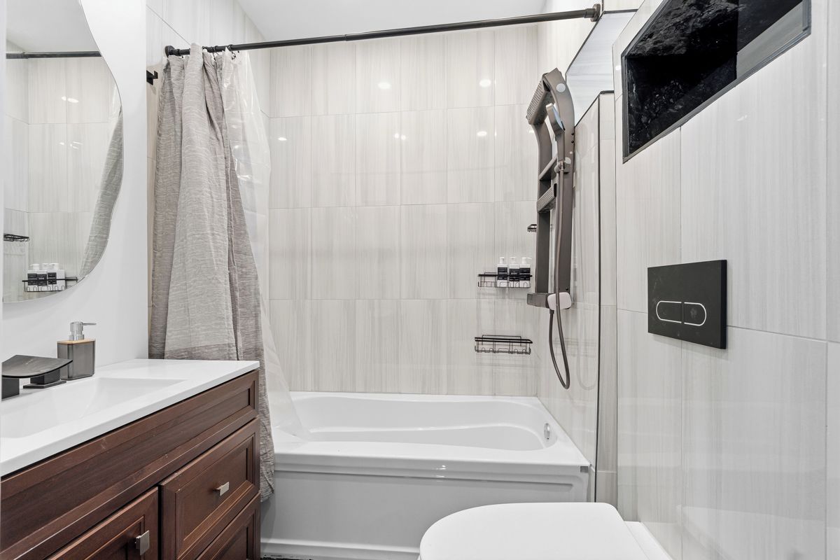 A modern bathroom with a bathtub, a shower, a vanity with a mirror, and a toilet.