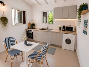 Una cocina moderna con zona de comedor, que incluye una mesa, sillas, un microondas, una lavadora y un fregadero.