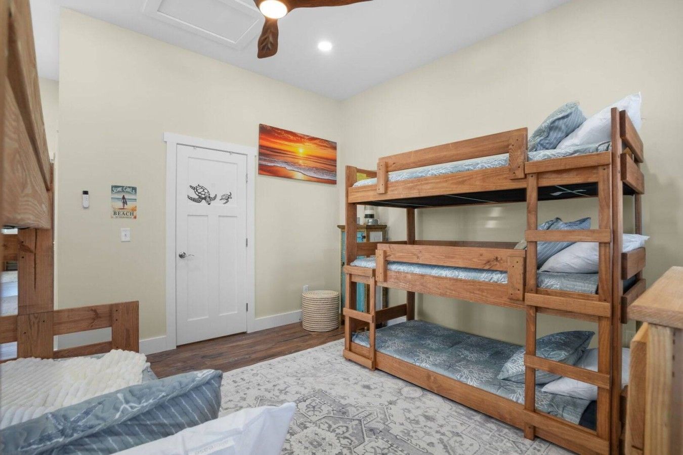 A room with bunk beds, a door, a wall art, and a patterned rug.