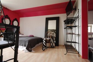 Quarto com cama de solteiro, uma cadeira, escrivaninha e prateleiras.