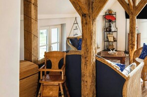 A rustic interior with exposed wooden beams, a wicker sofa, and a hanging chair.