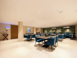 Uma ampla área de jantar com várias mesas e cadeiras, um painel decorado e um aparelho de ar condicionado.