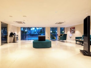 Um hall amplo com uma grande janela, uma área de estar circular e uma televisão.