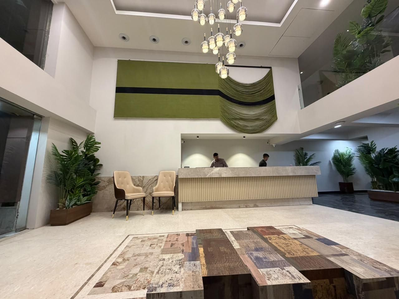 A reception area with a marble floor, a reception desk, two chairs, and a chandelier.