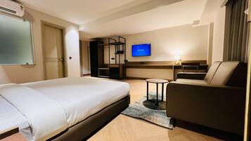 A hotel room with a bed, a sofa, a TV, and a small table.